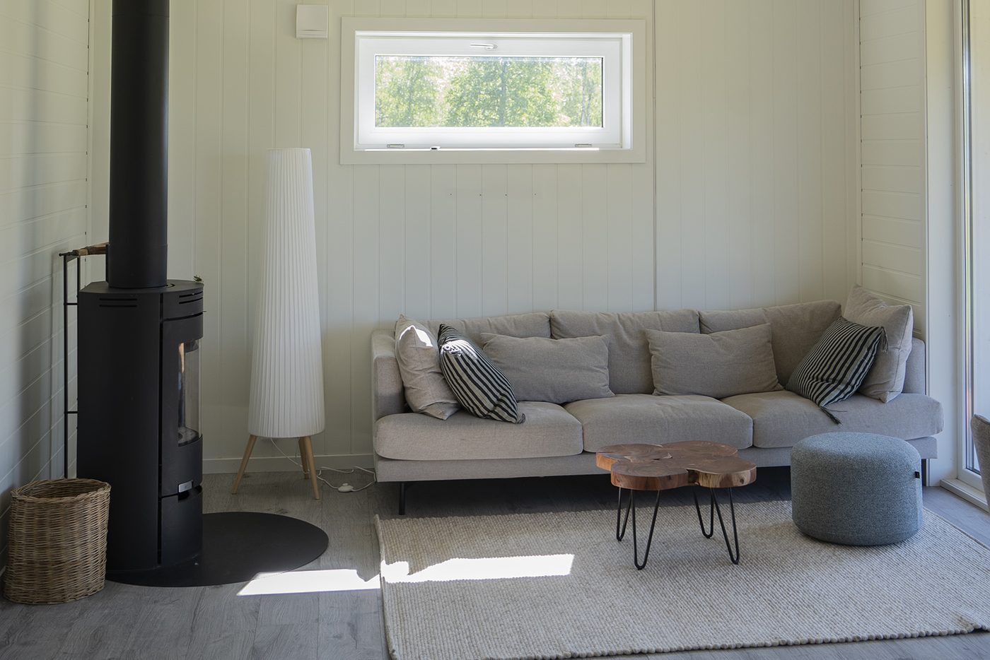 Vardagsrum i Ängåsen 3 med vedkamin, soffa och panoramafönster mot naturen