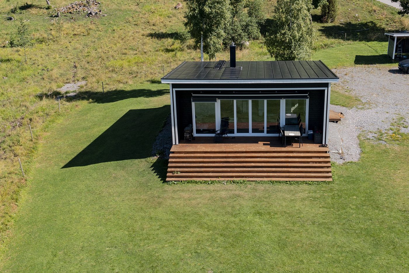 Ängåsen 2 - modern stuga med mörk träfasad, stort glasparti och brett trädäck
